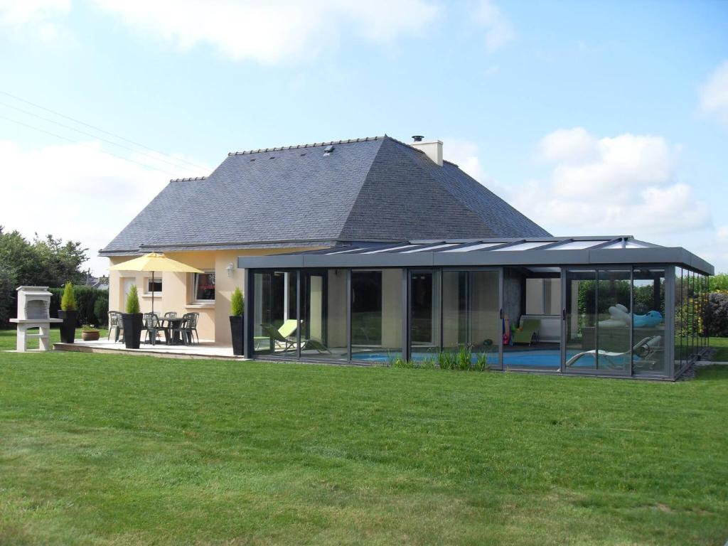 a house with a conservatory on a lawn at Brittany, House with swimming pool and spa in the countryside in Kersaint-Plabennec
