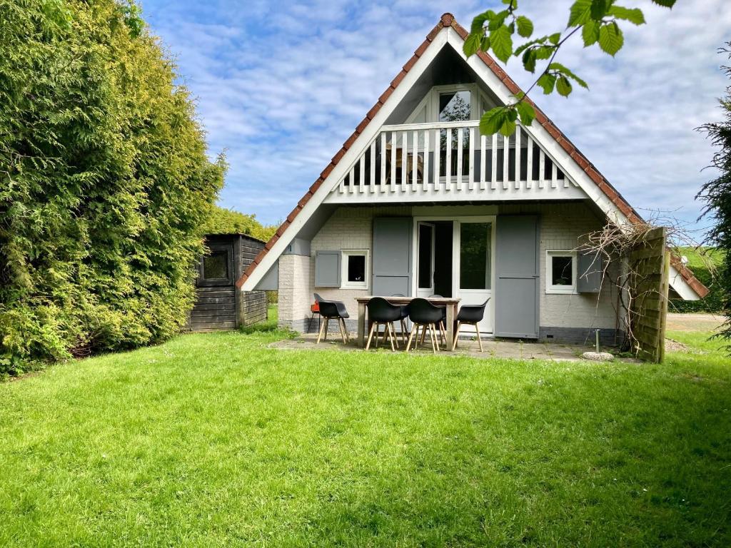 une maison blanche avec des chaises et une table dans la cour dans l'établissement Olivia 6pers House with a private garden close to the National Park Lauwersmeer, à Anjum