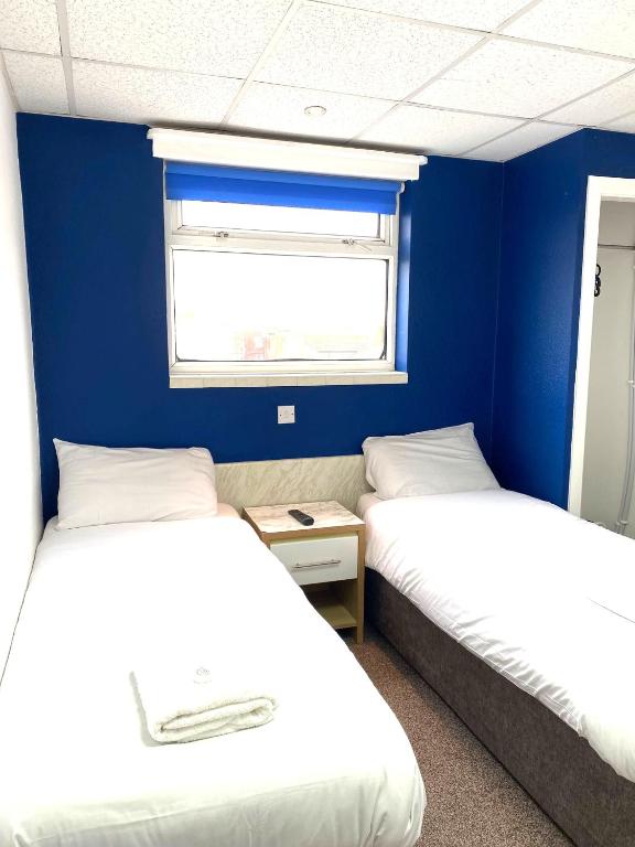 two beds in a room with a blue wall at The Regency Hotel in Blackpool