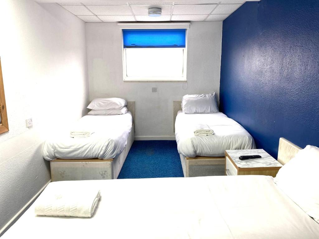 a small room with three beds and a window at The Regency Hotel in Blackpool