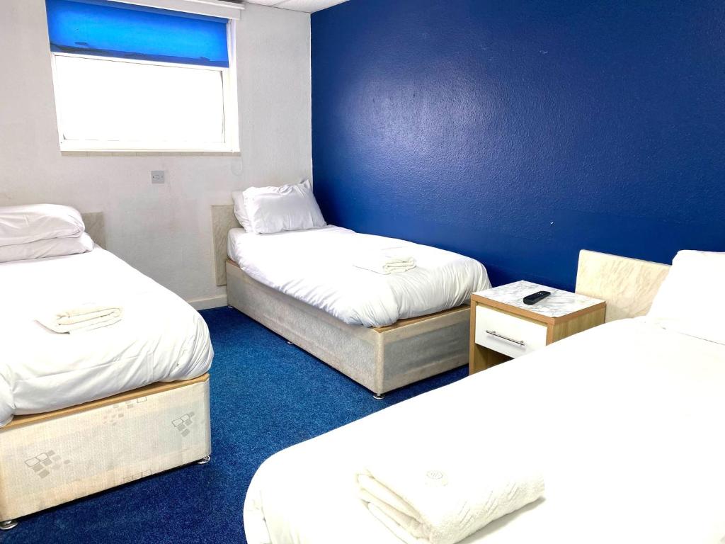 a room with two beds and a blue wall at The Regency Hotel in Blackpool