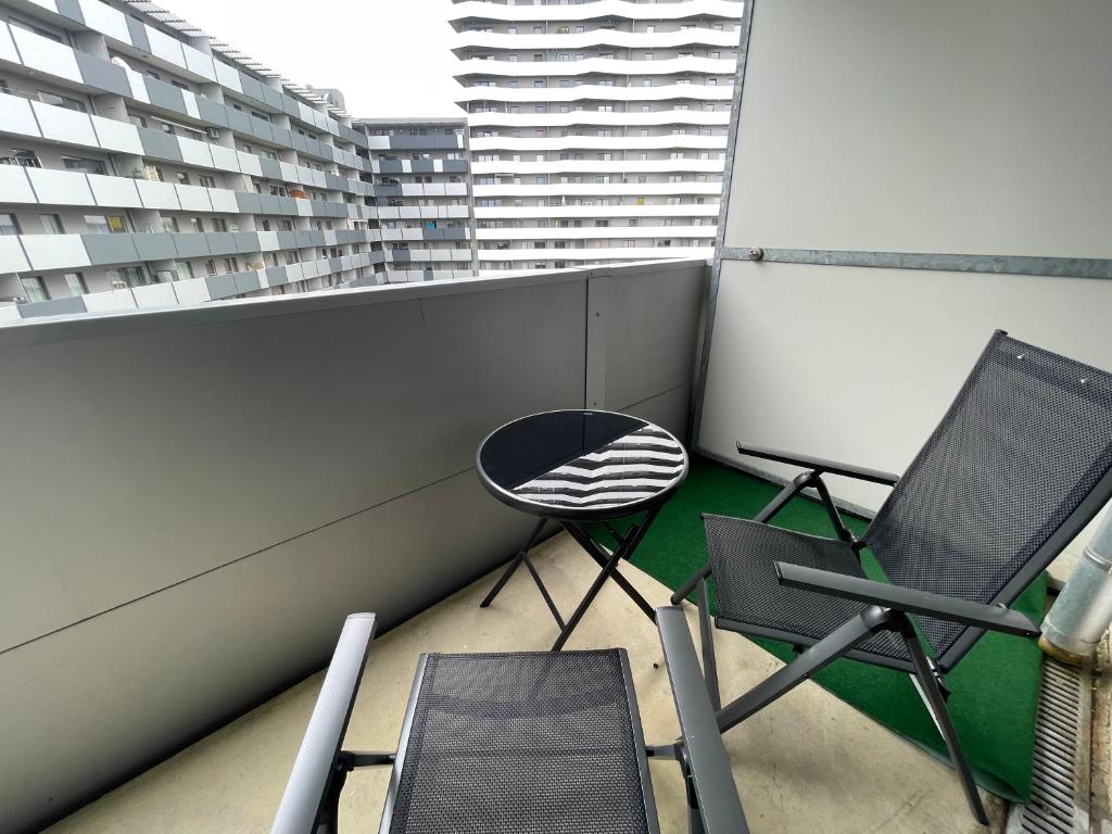 einen Balkon mit zwei Stühlen und einem Tisch darauf in der Unterkunft Spacious 1BR Apartment with Balcony above Citygate Shopping Complex with Metro Access in Wien