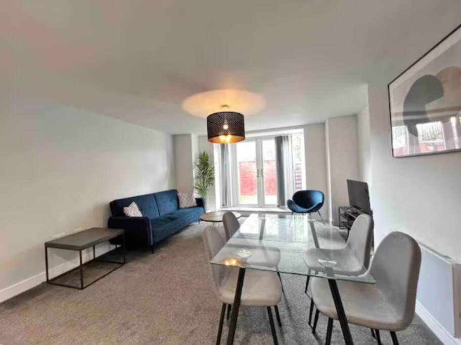 a living room with a glass table and a blue couch at FREE PARKING - Stunning 2-BR near Salford Royal in Manchester