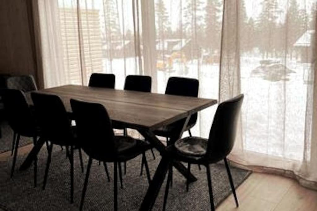 a dining room table with chairs and a large window at Nybyggt parhus - ink städ, handdukar & sängkläder in Sälen