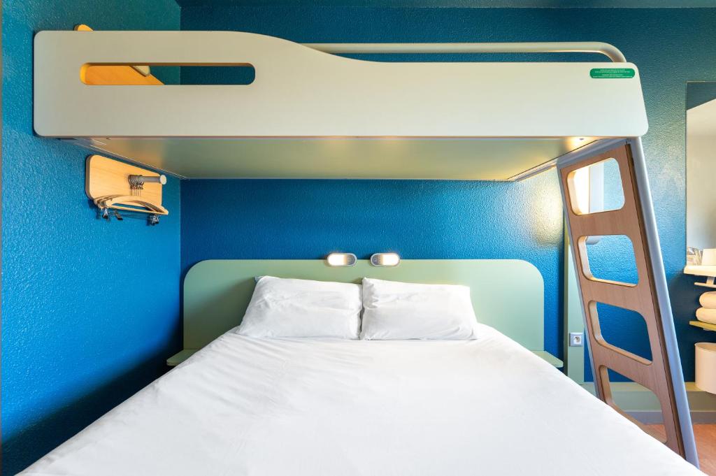 a bed in a blue room with a bunk bed at ibis budget Mâcon Nord in Mâcon