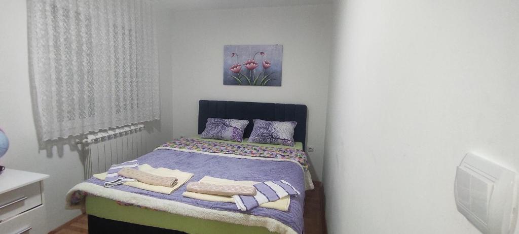 a bedroom with a bed with purple sheets and pillows at Apartman LARA in Pirot