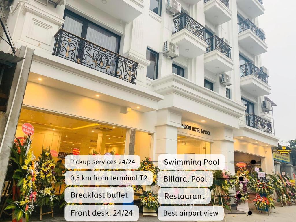 a white building with signs in front of it at Paragon Noi bai Hotel & Pool in Hanoi