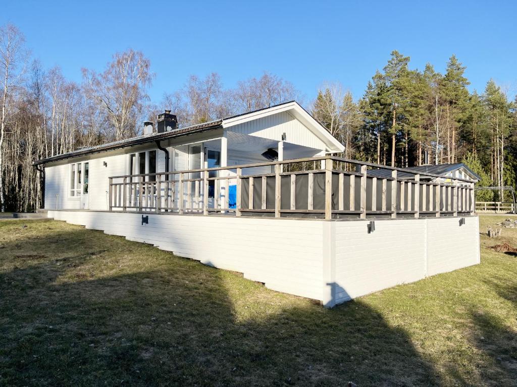 ein weißes Haus mit einer Terrasse auf einem Feld in der Unterkunft Nice cottage located by the lake Nommen in Björköby