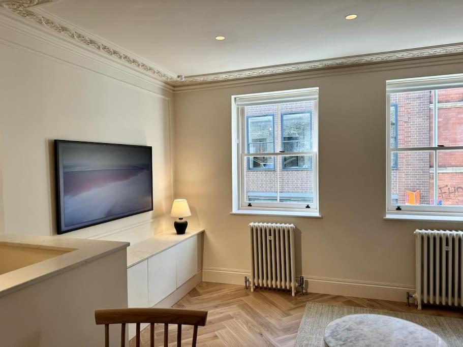 a living room with a flat screen tv and two windows at Luxury Shoreditch One Bedroom Apartment in London