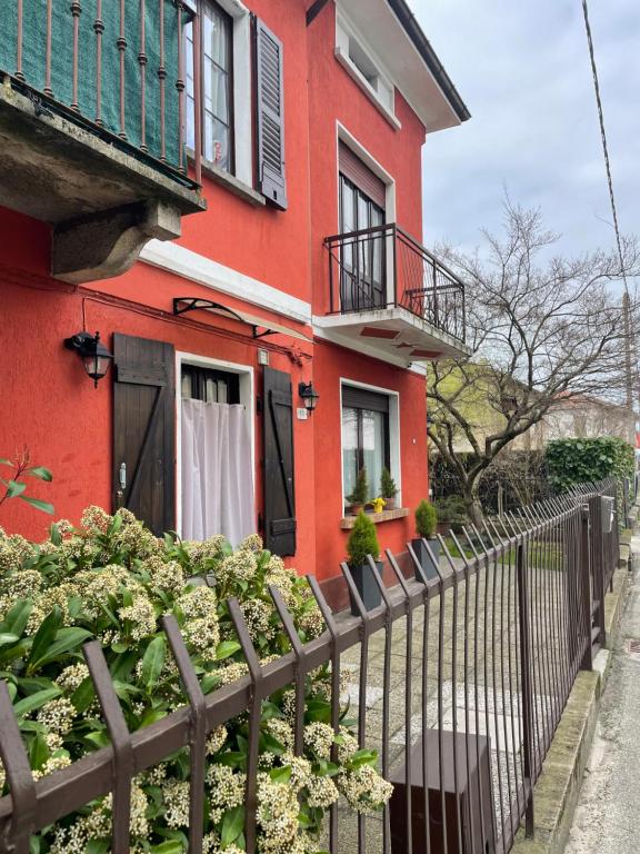 ein rotes Haus mit einem Zaun und Blumen in der Unterkunft Bnbook Casa Giolito in Castelletto sopra Ticino