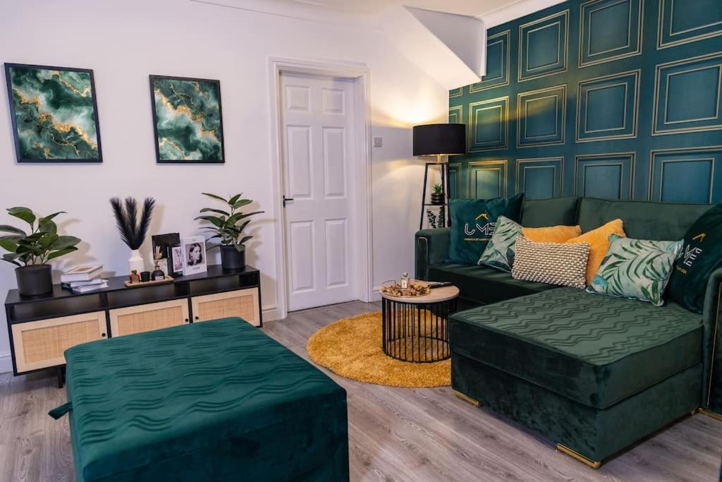 ein Wohnzimmer mit einem grünen Sofa und einem Tisch in der Unterkunft A Cosy, Elegant 3 Bed Suite in Killingbeck