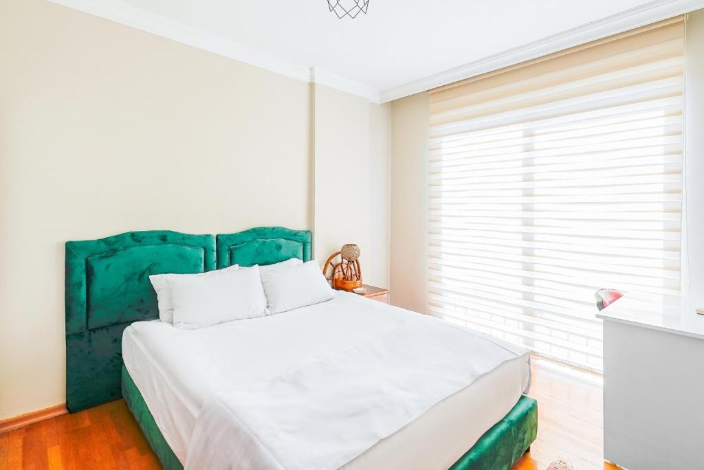 een slaapkamer met een groot bed met een groen hoofdeinde bij Cozy Flat with Balcony 10 min to Hadrian Gates in Antalya