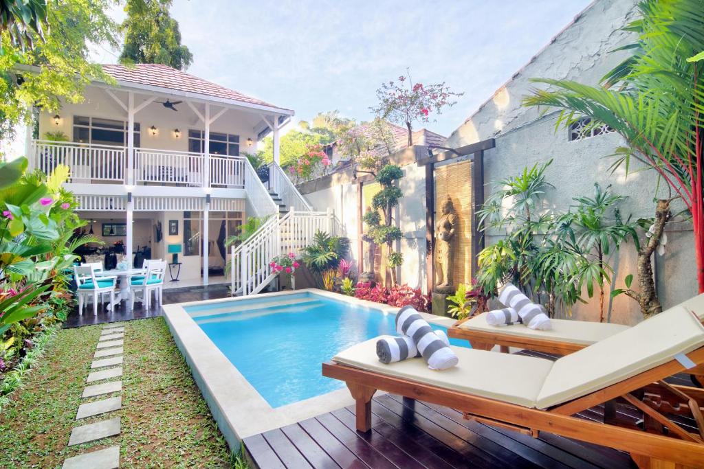 a backyard with a swimming pool and a house at Selasih Beach House in Seminyak