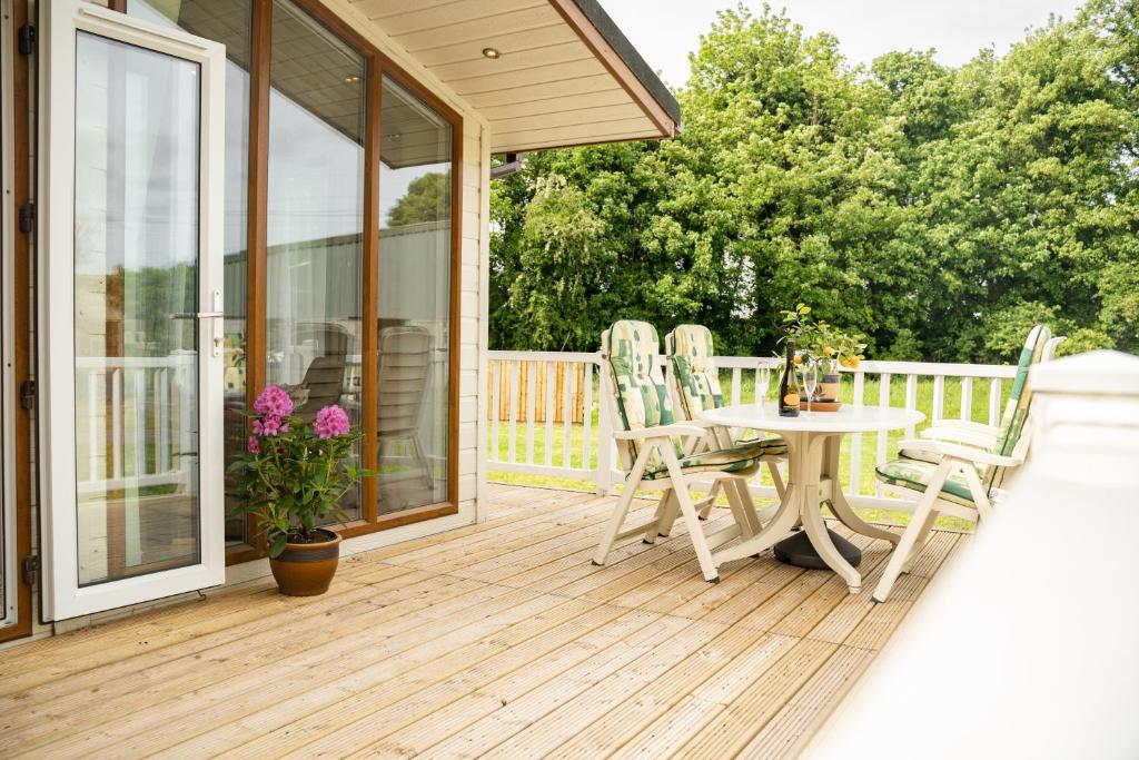 una terraza de madera con mesa y sillas. en Recently updated lodge near Chester city centre - For up to 6, en Chester