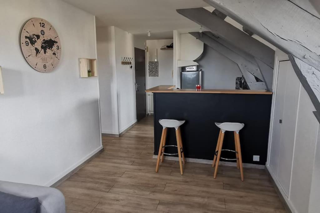 eine Küche mit zwei Hockern und einer Theke in einem Zimmer in der Unterkunft apt cozy refait à neuf à 5min du centre ville in Saint-Hilaire-du-Harcouët