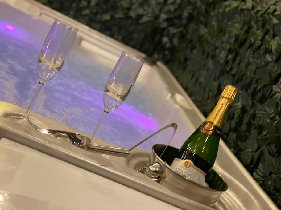 a bottle of champagne and two glasses on a table at Luxury Urban Hideaway with private hot tub in Croydon