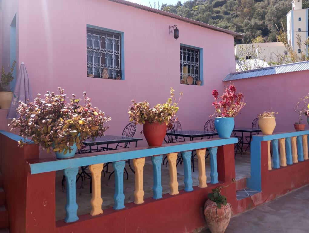 ein rosafarbenes Haus mit Topfpflanzen auf einem Geländer in der Unterkunft Dar Lala Zhour in Aïn Bouchrik