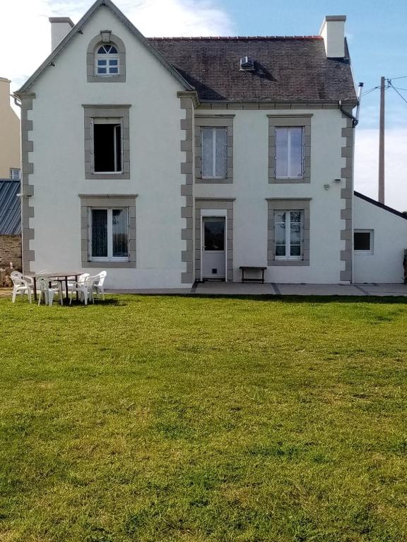 une grande maison blanche avec une table de pique-nique dans une cour dans l'établissement Maison Bretonne, à Cléden-Cap-Sizun