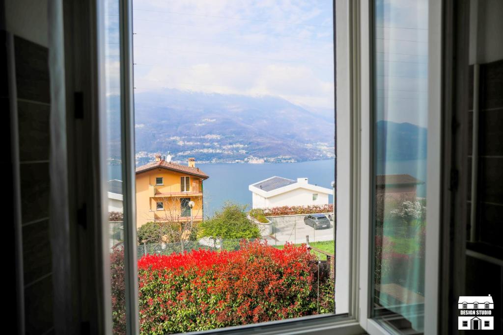 een raam met uitzicht op het water en de gebouwen bij Villa Lena in Bellano