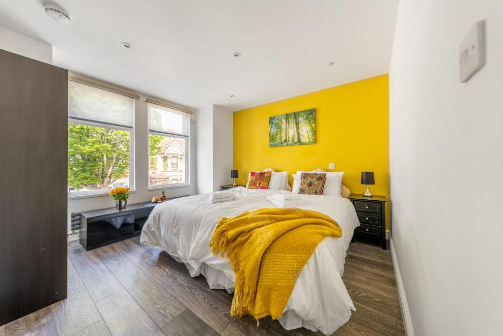 um quarto com uma cama grande e uma parede amarela em VitiLevu House em Southall