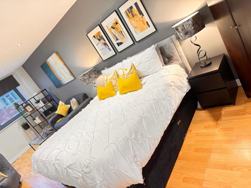 a bedroom with a large bed with yellow pillows at Perfectly Located City Centre Studio Apartment - West One with FREE WIFI, GYM ACCESS, NETFLIX in Sheffield
