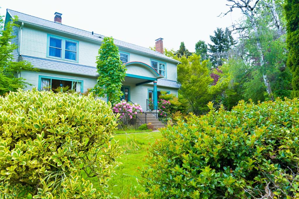 una casa azul con arbustos en el patio en Riverpath Inn, en Eugene