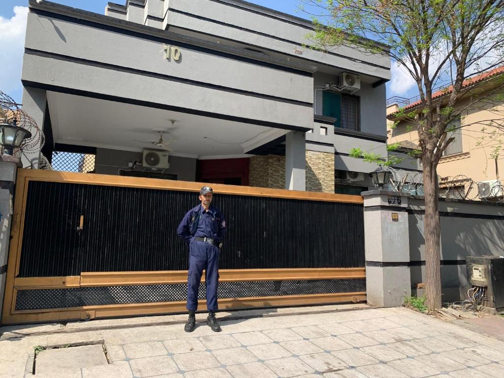 a police officer standing in front of a house at Hayat Grand Guest House in Islamabad