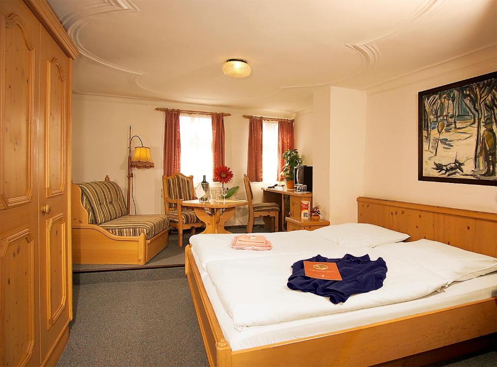 ein Schlafzimmer mit einem Bett, einem Stuhl und einem Tisch in der Unterkunft Altdeutsches Gasthaus Roter Hirsch in Jena
