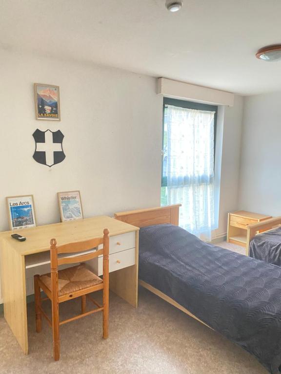 1 dormitorio con cama, escritorio y ventana en Auberge le bois du cornet, en La Forclaz