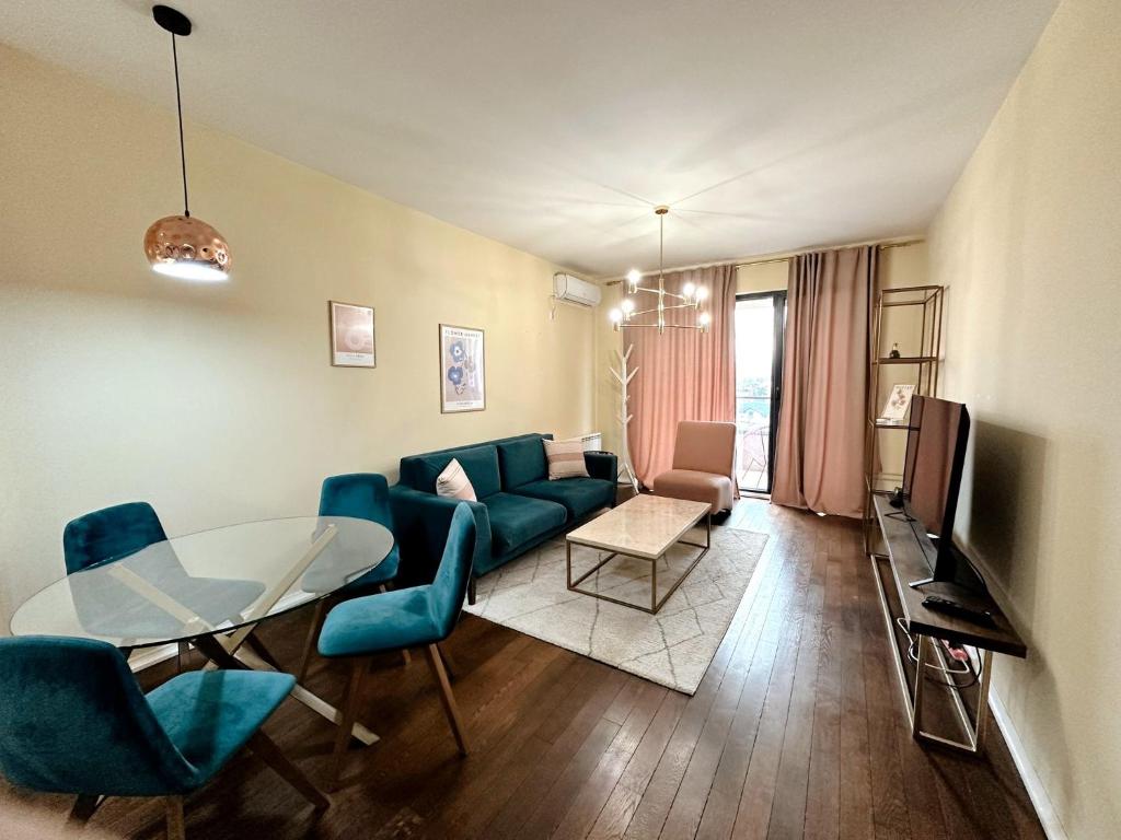 uma sala de estar com um sofá azul e uma mesa de vidro em The Golden Sunset flat em Skopje