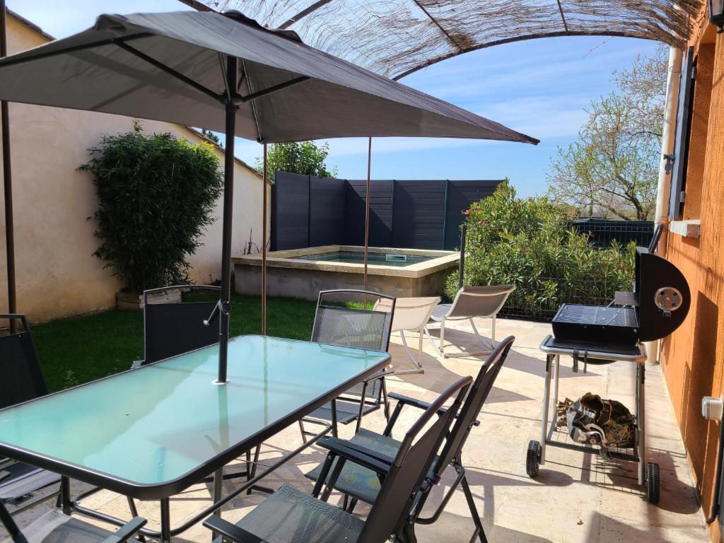 a table and chairs with an umbrella on a patio at Le temps d'une pause in Villes-sur-Auzon