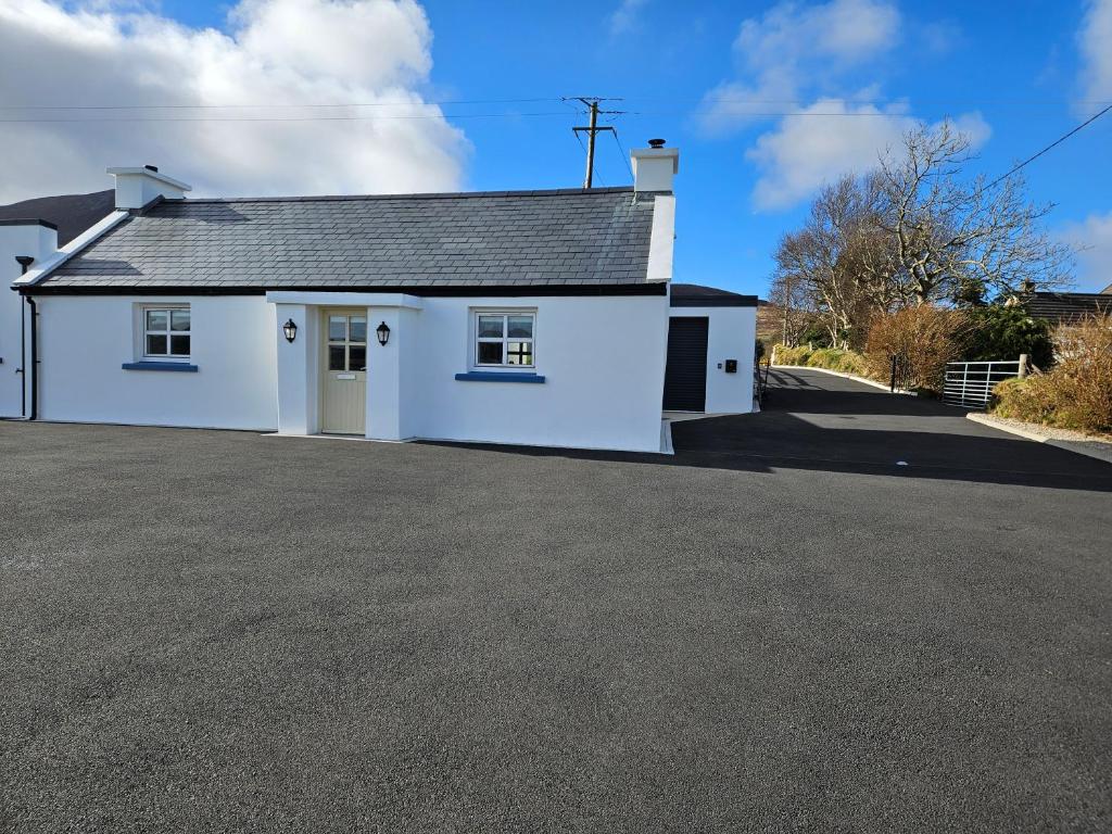 ein weißes Haus mit Auffahrt in der Unterkunft Cosy 1 bedroom cottage, Ideal quiet getaway. in Creeslough
