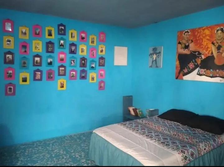 a bedroom with a blue wall with pictures on the wall at POSADA HORTENCIA in Aguascalientes