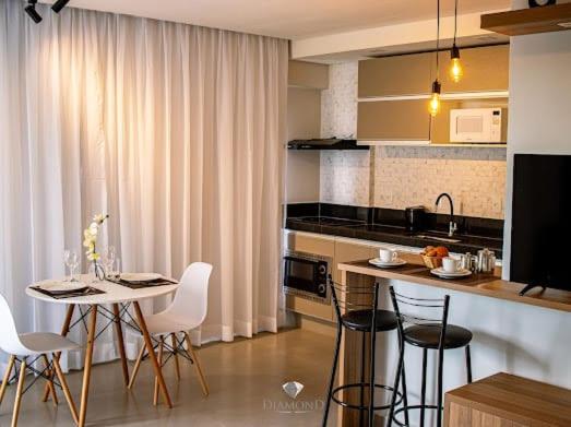 a kitchen with a table and some chairs and a counter at Diamond Hotéis e Flats in São Lourenço