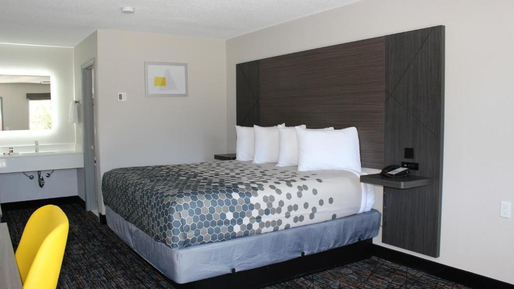 a hotel room with a bed and a yellow chair at Landsford Inn in Fort Lawn