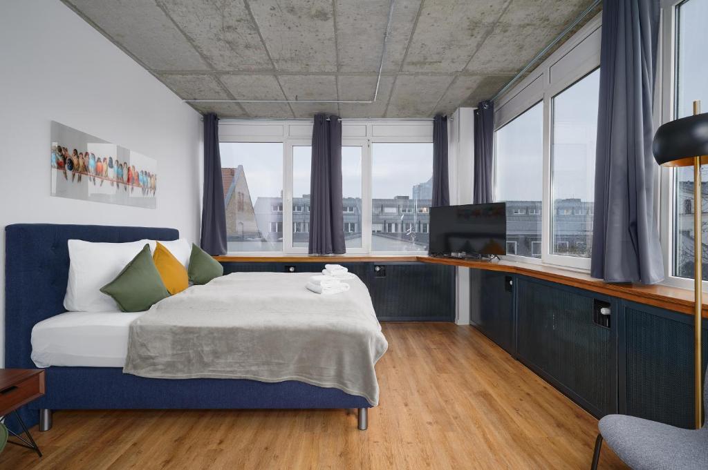 Stylisches Studio im Herzen Leipzigs في لايبزيغ: غرفة نوم مع سرير ودواليب زرقاء ونوافذ