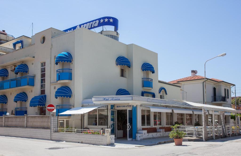 a large white building with blue balconies on a street at HOTEL AZZURRA in Senigallia