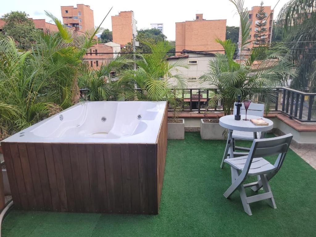 een hot tub op een balkon met een tafel en een stoel bij The Emerald, Medellin in Medellín