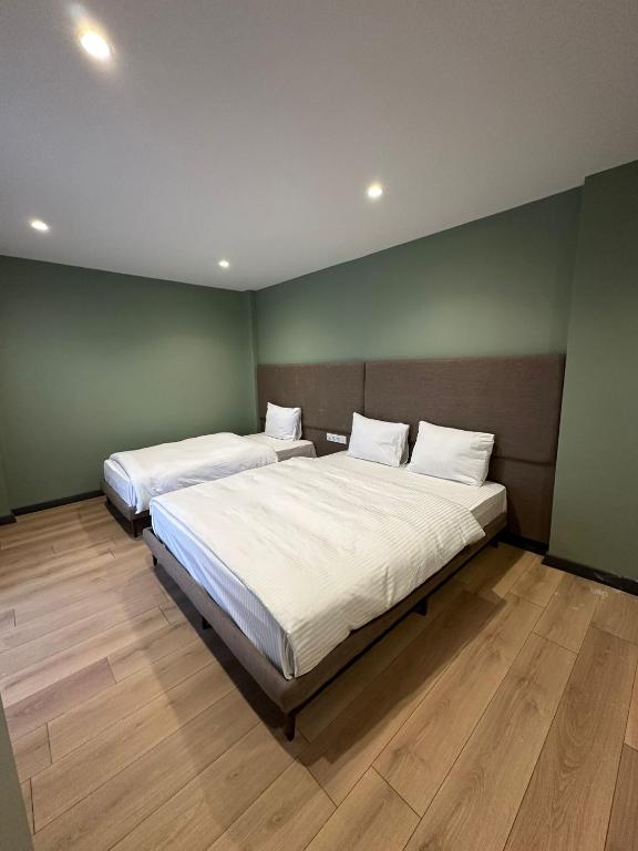 two beds in a room with green walls and wooden floors at Heaven Inn Airport Hotel in Arnavutköy