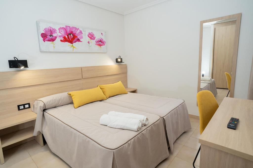 1 dormitorio con 1 cama con almohadas amarillas y blancas en Hotel La Perdi, en Sant Mateu