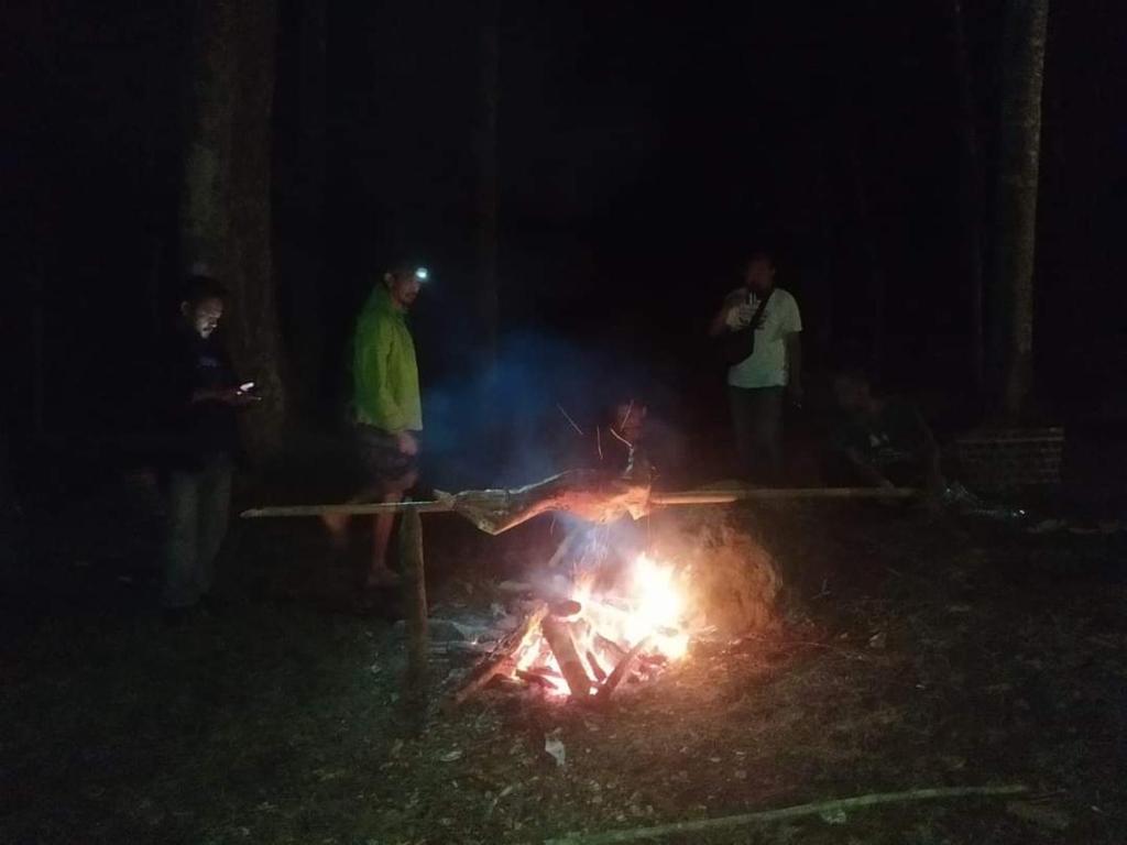 a group of people standing around a fire at night at Joben Evergreen Camp in Tetebatu