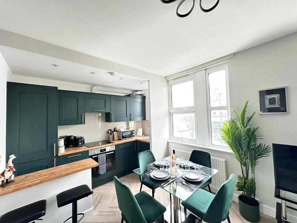 a kitchen with green cabinets and a table and chairs at Stunning 2-Bed Apartment Fully Equipped - Clapham Junction - Battersea - 5 Minutes Train Station in London