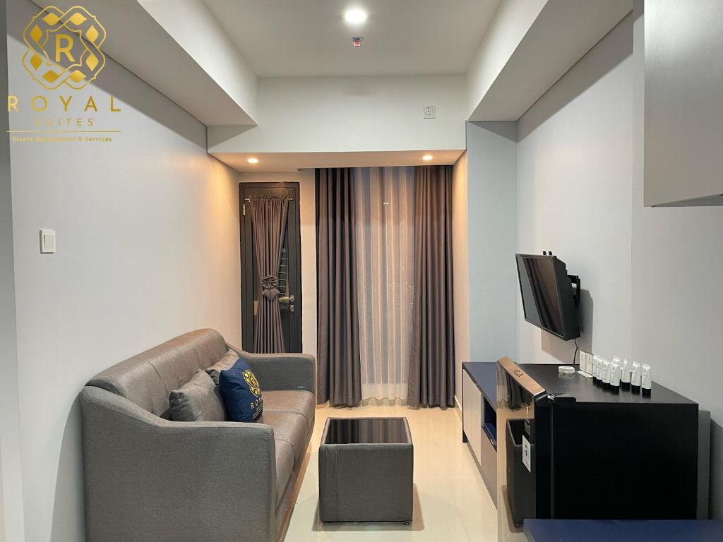ein Wohnzimmer mit einem Sofa und einem TV in der Unterkunft Apartment Pollux Habibie 2BR 11th Floor By Royal Suites in Batam Center