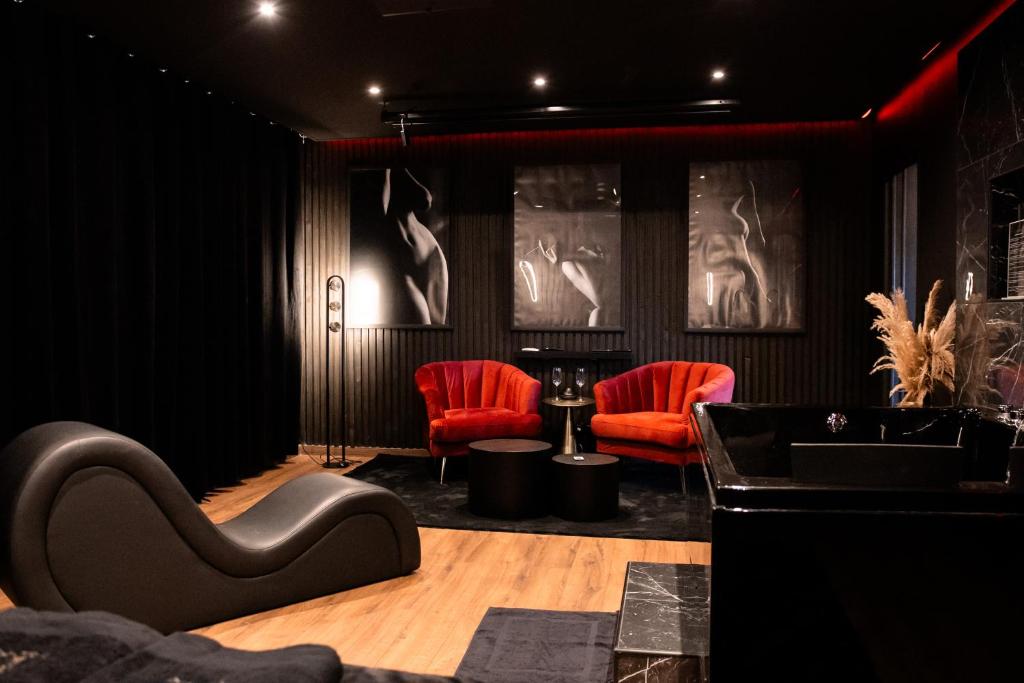 a salon with two red chairs and a table at BlackRoom Suite de Luxe 50 Nuances de grey in Le Havre