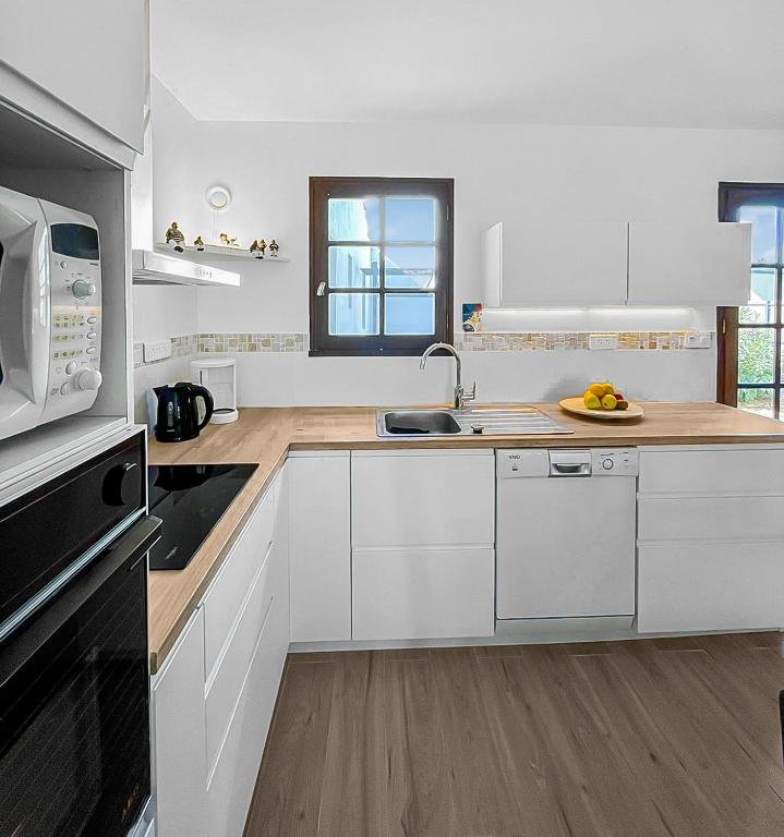 une cuisine blanche avec un évier et un micro-ondes dans l'établissement Havre de Lumière à La Barre-de-Monts, à La Barre-de-Monts