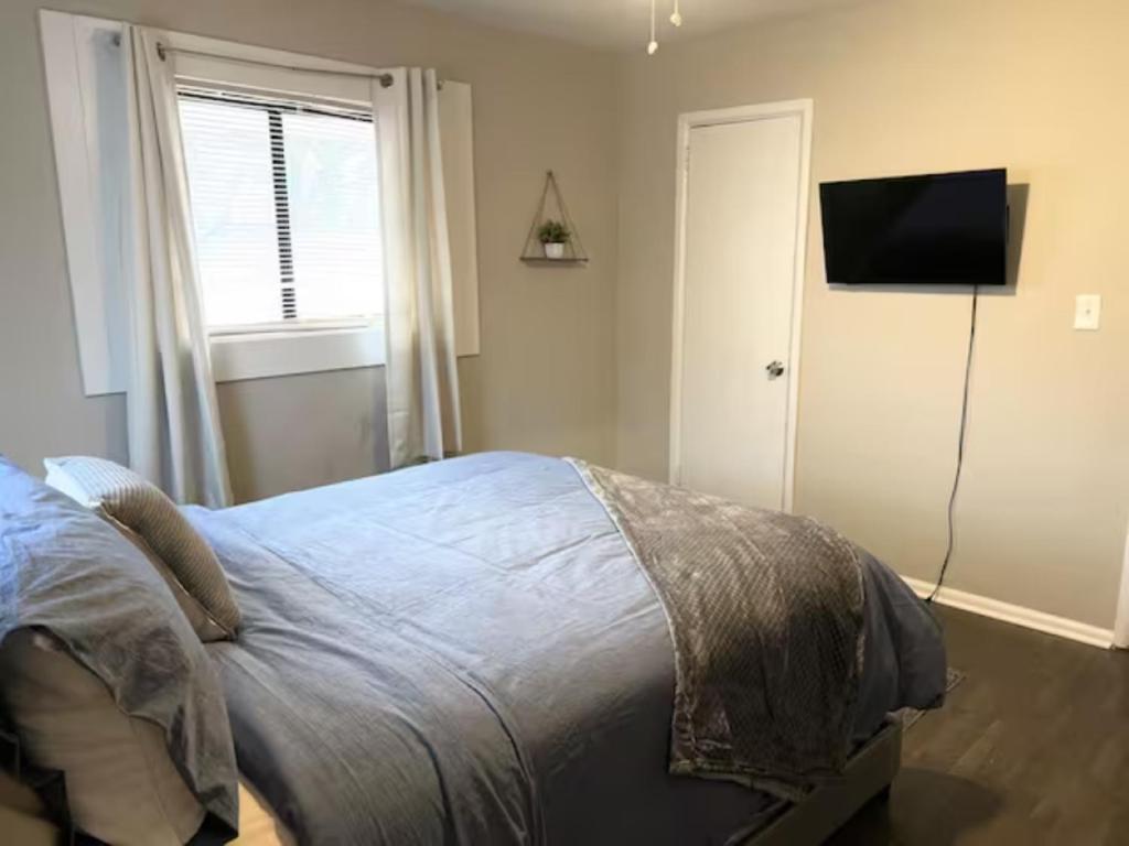 um quarto com uma cama e uma televisão de ecrã plano em Queen Suite - Hot Tub - Wifi Room 2 em Forest Park