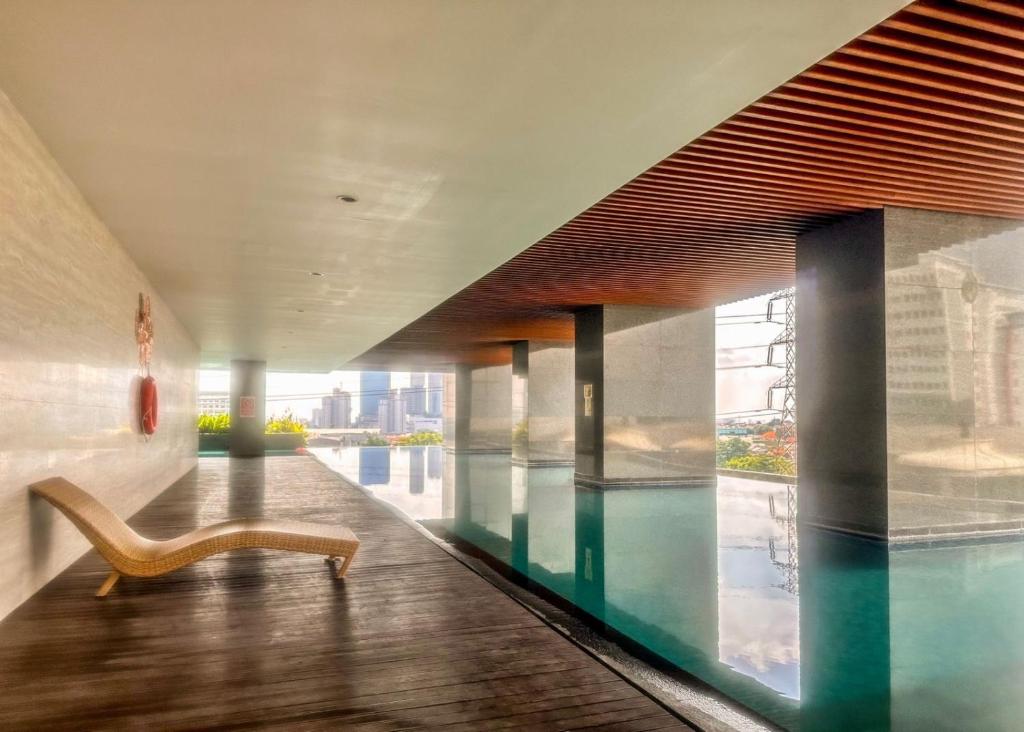 a swimming pool with a chair in a building at Grand Sungkono Lagoon Apartment 2BR Surabaya by Le Ciel Hospitality in Surabaya