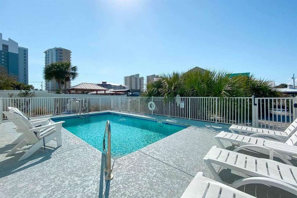 einen Pool mit weißen Stühlen und einem Zaun in der Unterkunft Summer at Family Bungalow w Pool! 4min Walk to Beach! in Gulf Shores