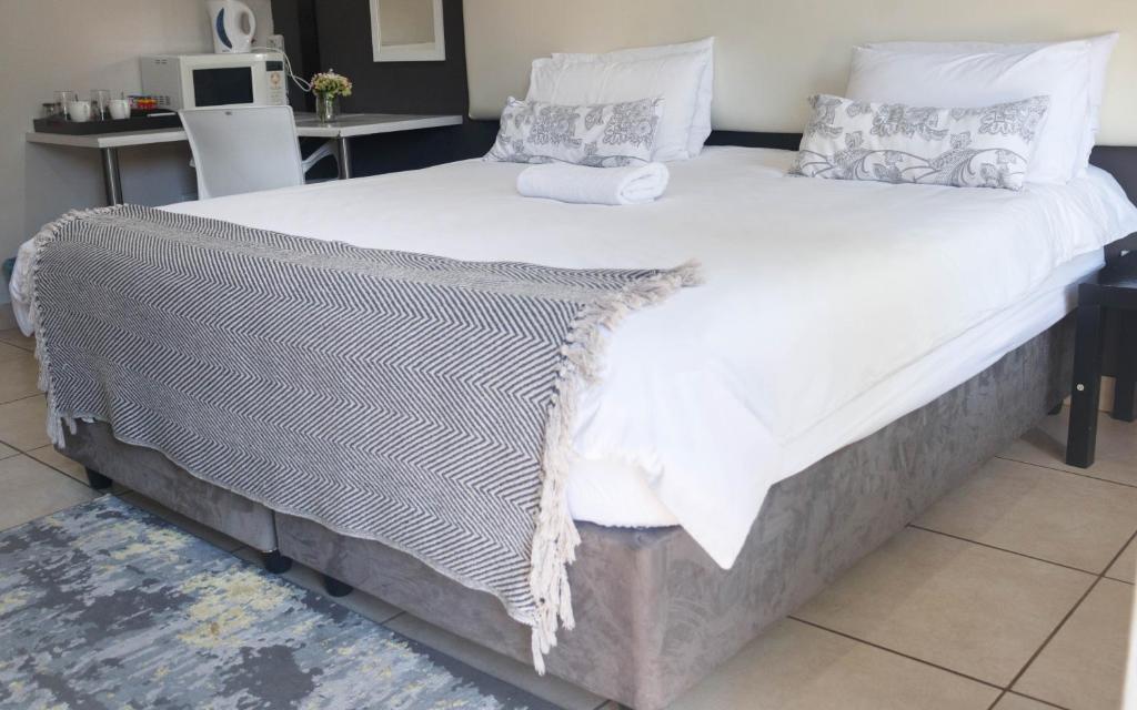 1 cama grande con sábanas blancas y almohadas. en 3 Liebeloft Guest House, en Edenvale