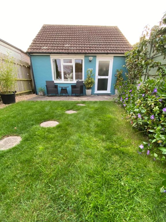 a backyard with a blue house and a green lawn at The Hut- Private 1 Bed Guesthouse in Lymington Town Centre, garden & parking in Lymington